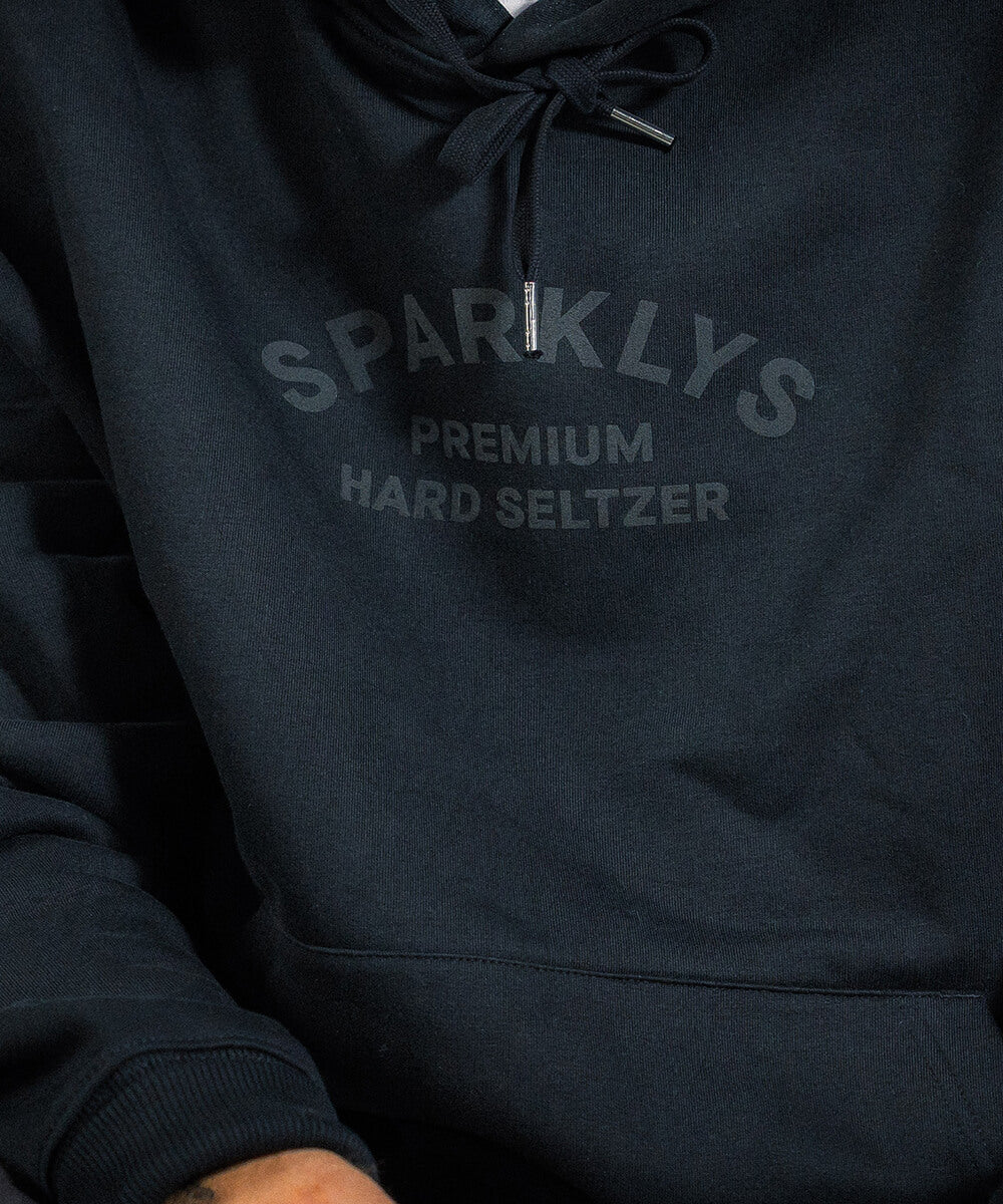 Nahaufnahme des subtilen schwarzen Vintage-Logos von Sparklys Hard Seltzer, gedruckt auf der Vorderseite des schwarzen Nutrition Facts Hoodies.